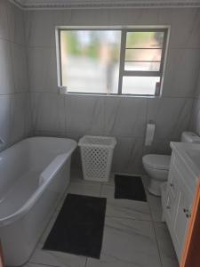 a bathroom with a tub and a toilet and a window at House 55D in Lichtenburg