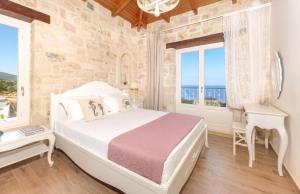 a bedroom with a bed and a desk and windows at The Yiameli Collection - Levandi in Zakynthos