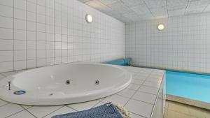a white bathroom with a tub and a swimming pool at Villavilla 247 - Ebeltoft, Østjylland in Ebeltoft
