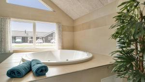 a large white tub in a bathroom with a window at Villavilla 451 - Grenå Strand, Østjylland in Grenå