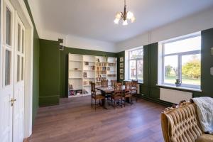 a dining room with green walls and a table and chairs at Bērzgala Viesu Nams in Stradi