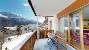 a balcony with a table and chairs and mountains at Apartment Macun in Silvaplana