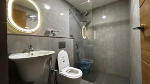 a bathroom with a sink and a toilet and a mirror at Cloud Nine Hotel - Kuthuparamba in Kūttuparamba