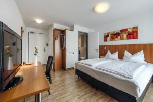 a bedroom with a bed and a desk and a television at Ratshotel - City Aparthotel Aalen in Aalen