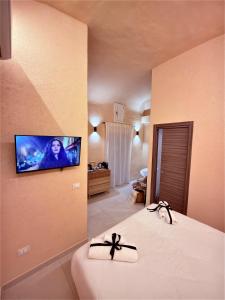 a bedroom with a flat screen tv on a wall at Bìfara Rooms in Palermo