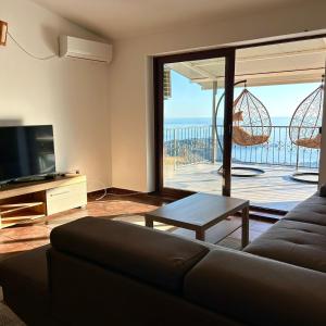 a living room with a couch and a television and a balcony at Villa Vistamar Lapcici in Budva