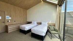 a room with two beds and a chair and a window at Guide Hill Station Lodge in Lake Tekapo