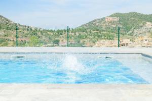 a swimming pool with blue water in front of a mountain at Beceite Camping in Beceite