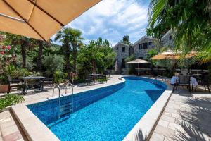 a pool with tables and chairs and an umbrella at Forte Rose Hotel in Herceg-Novi