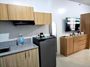 a kitchen with a black refrigerator and wooden cabinets at Cozy Plumera Studio near Mactan Airport in Bankal