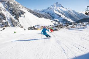 a person is skiing down a snow covered mountain at Hotel Steffisalp - Ski-in & Ski-out am Arlberg in Warth am Arlberg