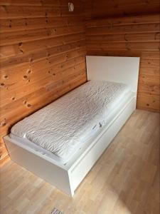 a white bed in a room with wooden walls at Sommarstuga med strandtomt in Ronneby +18 photos