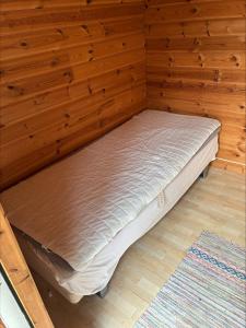 a bed in a room with wooden walls at Sommarstuga med strandtomt in Ronneby