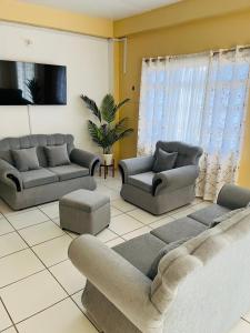 a living room with two couches and a couch at Lyn Tropical Getaway in Port-of-Spain