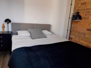 a bed with two pillows and a brick wall at LOFT Jana z Kolna in Koszalin