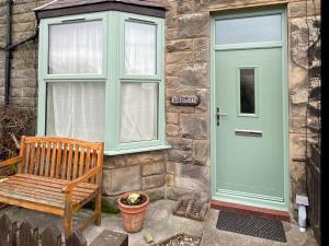 a green door and a bench next to a building at Kittiwake Cottage, Seahouses in Seahouses