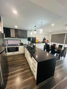 a large kitchen with a black counter top and a table at My Home II in Tarneit +7 photos