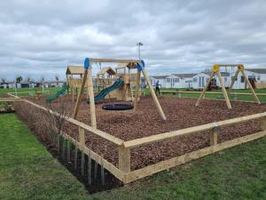 a playground with a swing set in a park at Leysdown Beach Escape in Sheerness