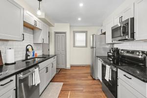 a kitchen with white cabinets and stainless steel appliances at Cozy 2BR Near Ohio State - Private Yard - Parking in Columbus