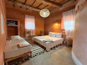 a bedroom with two beds and a chandelier at Tigmi Hamid Découverte des traditions et de la culture berbère in Aït Benhaddou