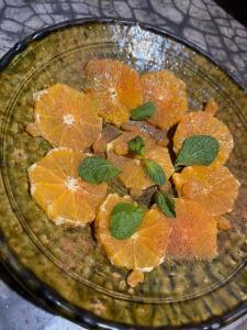 a glass bowl filled with orange slices and green leaves at Tigmi Hamid Découverte des traditions et de la culture berbère in Aït Benhaddou