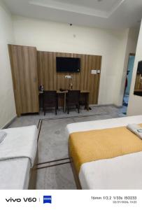 a room with two beds and a table with a television at HR King HOTEL in Amritsar