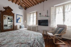 ein Schlafzimmer mit Bett, Stuhl und Fernseher in der Unterkunft Spacious 2BR Apartment for Families Central & Quiet Pisa in Pisa