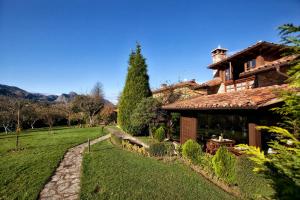a house with a grass yard next to a building at Hotel-Apartamentos La Arquera in Llanes