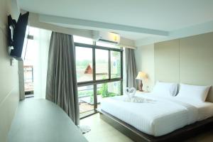 ein Schlafzimmer mit einem weißen Bett und einem großen Fenster in der Unterkunft A Plus Deluxe Hotel in Ko Lipe