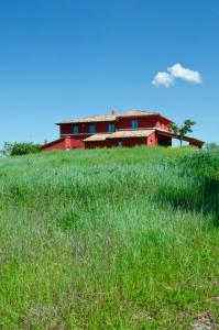 a red building on top of a grassy hill at Al Dolce Far Niente Dimora con piscina di Design in San Biagio della Valle