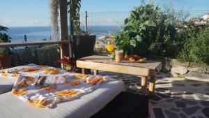 a table and a bench on a patio with the ocean at casa2sonhos in Água de Pena