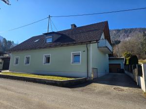 a white house with a black roof on a street at Ferienwohnung U28 in Ferlach