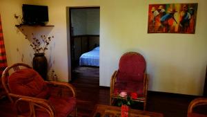 a living room with two chairs and a bed at Eco Lodge Les Chambres Du Voyageur in Antsirabe