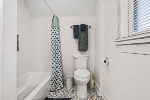 a bathroom with a toilet and a shower curtain at Luxe 2BR Franklinton - Private Patio - 2Car Garage in Columbus