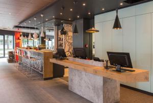 a restaurant with a bar with a computer on the counter at Ibis Muenchen Airport Sued in Hallbergmoos