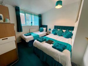 ein Hotelzimmer mit zwei Betten und blauen Kissen in der Unterkunft Beeches Hotel in Blackpool