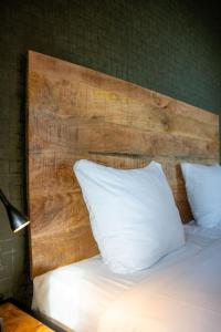 a bed with a wooden headboard and a white pillow at Havezathe Carpe Diem in Vethuizen