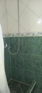 a shower with a hose in a green tile bathroom at Habitaciones Cecy in General Juan Madariaga
