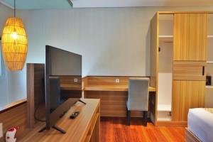 a bedroom with a desk and a tv in a room at The New Moon Umalas in Seminyak