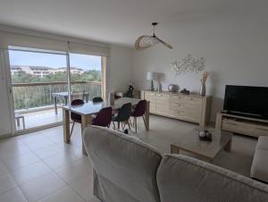 a living room with a table and chairs and a television at Les Terrasses De Vignola in Porto-Vecchio