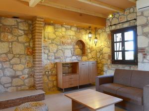 a living room with a couch and a stone wall at Petrino in Vourvourou