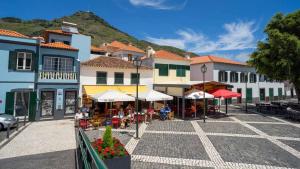 a group of buildings with tables and umbrellas in a street at Surf Nest in Machico