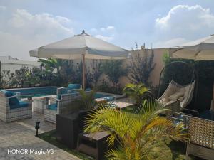 a patio with chairs and an umbrella and a pool at Loay Villa Stella Helipolis in Madīnat aţ Ţalāʼi‘