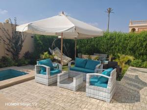 a group of chairs and an umbrella next to a pool at Loay Villa Stella Helipolis in Madīnat aţ Ţalāʼi‘