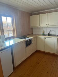 an empty kitchen with white cabinets and a sink at Tyinholmen hytter in Eidsbugarden