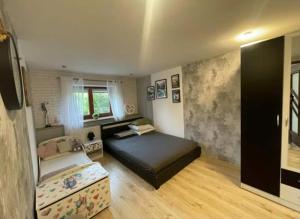 a bedroom with a bed and a couch in it at Domek Pluto Konradów 1 in Lądek-Zdrój