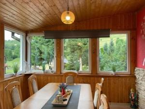 a dining room with a table and some windows at Domek Pluto Konradów 1 in Lądek-Zdrój