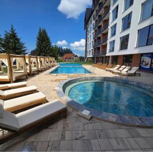 a swimming pool with lounge chairs and a building at Misho Hills Retreat in Kopaonik