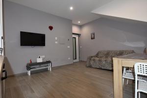 a living room with a couch and a tv on the wall at House Nonno Viky in Volla