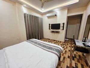 a hotel room with a bed and a flat screen tv at Crestview Inn in Lucknow +31 photos